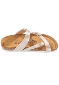 Ljust beige sandaler med flera korsande remmar, en texturerad korkfotbädd och en gummisula. Har en silverfärgad spänne som accent.