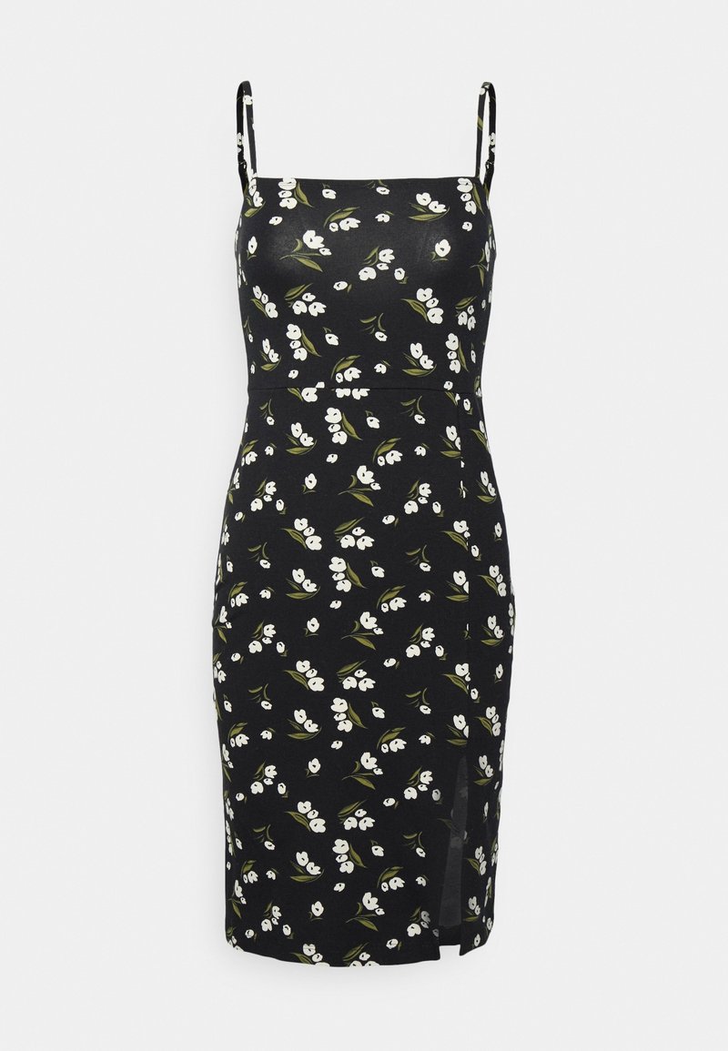 Robe noire sans manches longueur genou avec motif floral blanc, fines bretelles, silhouette ajustée et une petite fente sur le côté.
