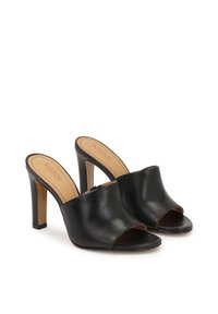 Mule din piele neagră, cu vârf deschis și toc înalt. Textură netedă, design rotunjit și o deschidere modestă în față. Logo-ul mărcii vizibil pe talpa interioară.