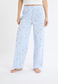 Pantalon de pyjama bleu clair à coupe ample, avec un motif ludique de figures colorées, une taille élastique, et une texture lisse et douce.