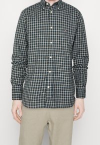 Camisa de botones en verde oscuro con un estampado de cuadros en blanco y azul claro. Cuenta con un collar abotonado y mangas largas.