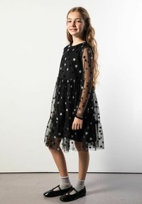 Czarna sukienka z wzorem gwiazd, przezroczystymi długimi rękawami, falbanianym dołem i dopasowanym gorsetem. Noszona z czarnymi butami i szarymi skarpetkami.