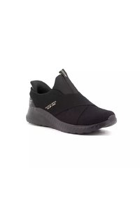 Sneaker nera slip-on con suola testurizzata, cinghie elastiche incrociate e linguetta, etichettata "Skechers Slip-Ins" sul lato.