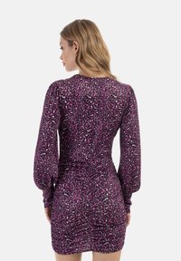 Raffiniertes lila Kleid mit Leopardenmuster, langen puffärmel, und einer figurbetonten Silhouette. Weicher Stoff mit glatter Textur.