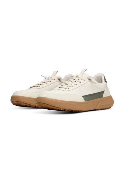 Sneaker in tessuto beige con suola in gomma color tan testurizzata e accento verde oliva sul lato. Presentano lacci rotondi e un design a profilo basso.