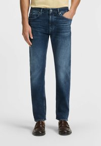 Blå denimjeans med rak passform, med framfickor, minimal urtvining och en klassisk femficksdesign. Bruna skor kompletterar looken.