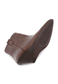 Bota de cuero marrón hasta el tobillo con tacón curvado, acabado suave, detalle de correa lateral y suela de goma texturizada con patrón acanalado.