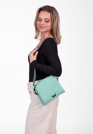 Mátově zelená křížová taška s texturovaným povrchem, zipem a vzorovaným popruhem s černými doplňky a detailem loga.