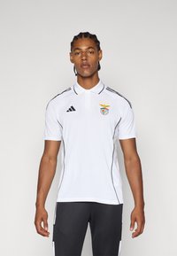 Hvit polo skjorte med svarte striper og logo, med klassisk krage og korte ermer. Laget av pustende materiale, med elegante design detaljer.