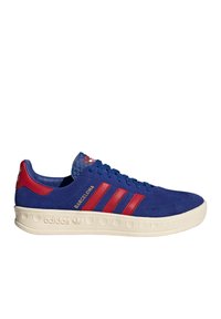 Blue suede sneaker with red accents, three red stripes, and a textured blue tongue. Features a cream rubber sole with rounded edges.