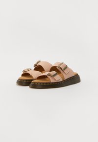 Sandales en cuir rose clair avec deux boucles réglables, semelle intérieure brun texturé et une semelle noire épaisse avec des coutures jaunes.