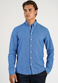 Camicia azzurra con bottoni realizzata in tessuto leggero. Presenta un colletto classico, maniche lunghe e bottoni bianchi sulla patta anteriore.