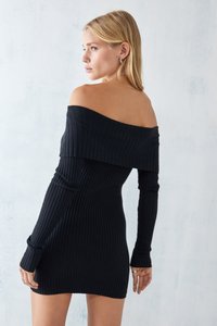 Svart avskjæringskjole med ribbestrikket stoff og lange ermer. Tettsittende design og midt på låret lengde. Glatt tekstur, minimale dekorasjoner.