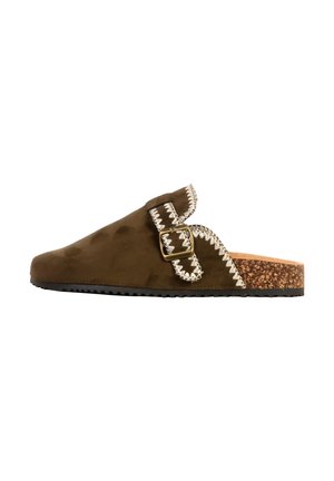 Sabot marron en daim avec couture zigzag blanche, boucle en laiton réglable et semelle en liège avec dessous en caoutchouc noir.