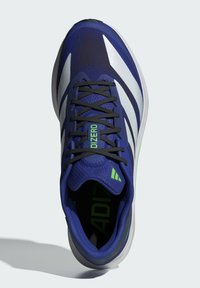 Blue athletic shoe with textured mesh upper, white stripes, and green accents. Features black laces and a cushioned sole.