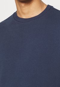 Pullover in cotone blu navy con collo a giro e texture liscia. Design semplice, senza motivi o dettagli visibili.