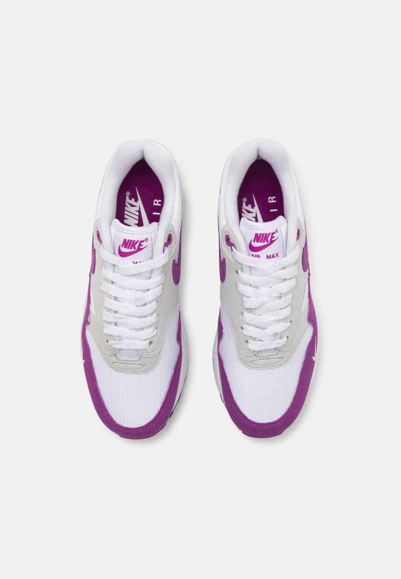 Een paar witte en paarse Nike Air Max sneakers met witte veters, paarse Nike swoosh en paarse interieurbranding, van bovenaf bekeken op een witte achtergrond.