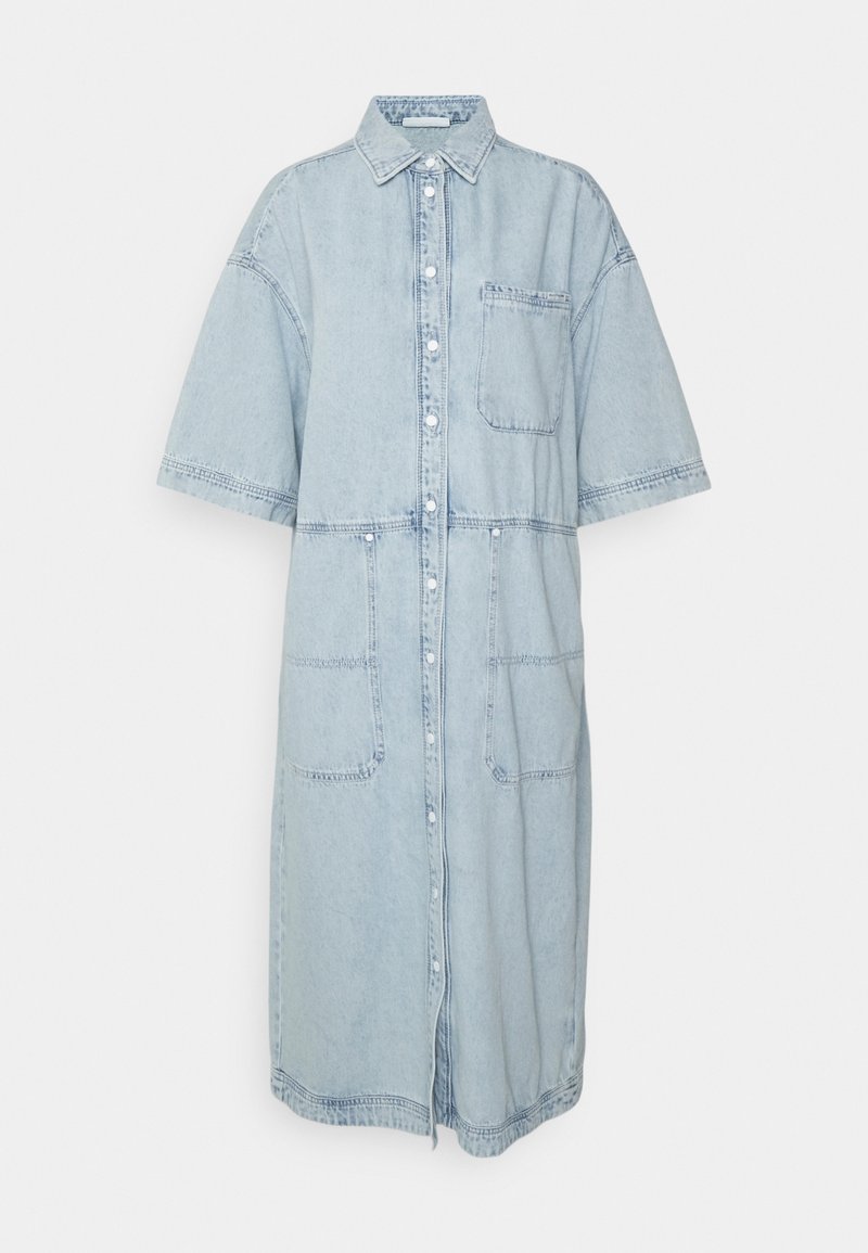 Vestido de camisa de mezclilla azul claro con mangas cortas, frente de botones, bolsillo en el pecho y dos bolsillos inferiores; presenta costuras de contraste y un ajuste relajado.