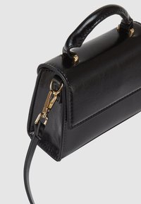 Sac à main en cuir noir de forme rectangulaire, avec une poignée supérieure, des accents en métal doré et une bandoulière amovible. Texture lisse.