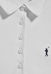 Polo shirt blanc avec un tissu texturé, doté d'une patte de boutonnage à trois boutons et d'une petite figure brodée en bleu marine sur la gauche.