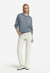 Ljusblå hoodie med långärmar, tillsammans med vita raka byxor och vita loafers. Enkelt design, minimala accenter.