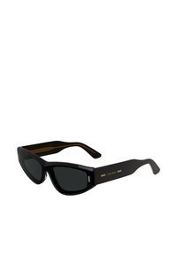 Black sunglasses with a sleek cat-eye shape. Glossy finish, solid dark lenses, and gold accents on the temples. Calvin Klein branding visible.