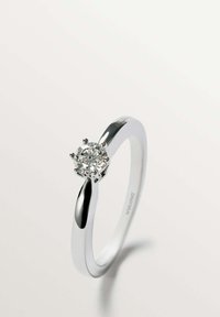 Anillo de plata con un diamante redondo y transparente sostenido por seis garras, con una banda lisa y pulida que se estrecha elegantemente hacia el engaste.