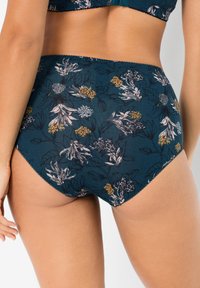 Costume da bagno a vita alta con stampa floreale, caratterizzato da uno sfondo teal con fiori gialli e rosa, texture liscia e bordi decorativi a scallop.