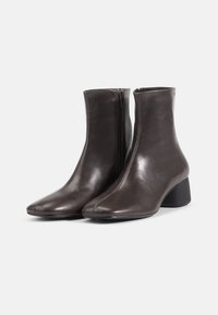 Brown leather ankle boots with a pointed toe, side zipper, and a block heel. Smooth texture with minimalistic design.