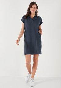 Navy polo dress with short sleeves, straight cut, side pockets, and a collar. Pairing with white sneakers, smooth fabric texture.
