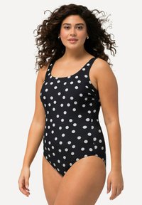 Maillot de bain une pièce noir à gros pois blancs. Il possède de larges bretelles, un col rond et une coupe ajustée pour le confort et la liberté de mouvement.