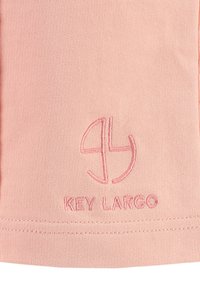 Helles pinkes Gewebe mit glatter Textur zeigt ein gesticktes Logo und den Text "KEY LARGO" am unteren Rand in passender Farbe.