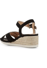 Sandalo a zeppa in suede nero con punta aperta, cinturino alla caviglia e piattaforma in juta intessuta. Presenta una suola testurizzata e un design minimalista.