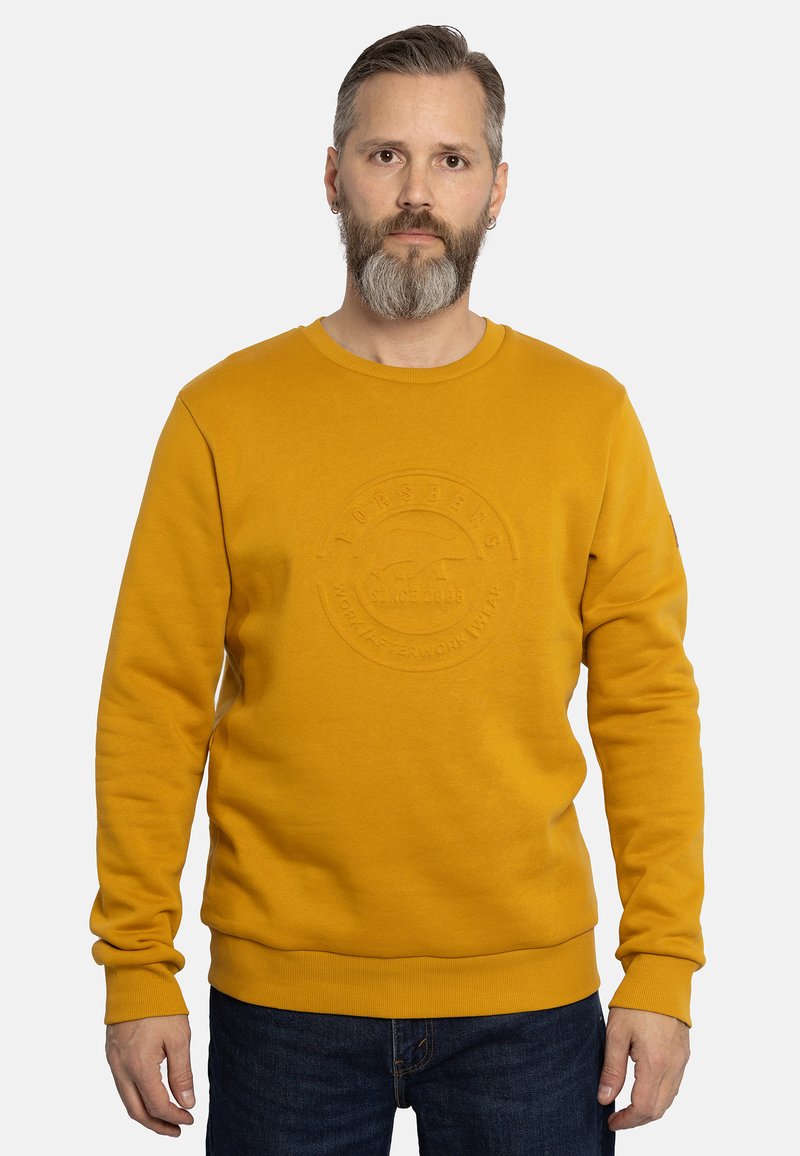 Sudadera amarilla con cuello redondo, que presenta un logo circular texturizado en el pecho. Mangas largas y puños y dobladillo acanalados.
