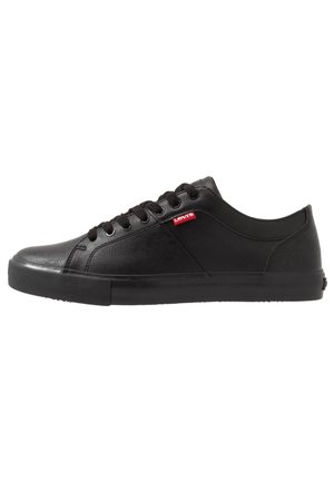 Sort lavtop sneaker med sorte snørebånd, gummisål og lille rød Levi's logo tag på siden.