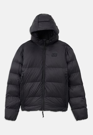 Black puffer jacket with a hood, featuring a boxy shape, quilted sections, zippered pockets, and a small logo patch on the chest.