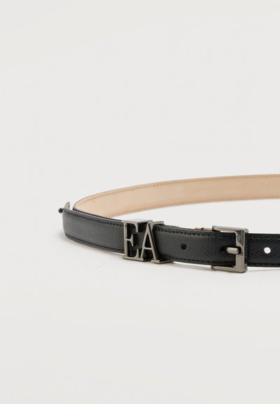 Μαύρη δερμάτινη ζώνη με υφή, με ασημένια αγκράφα και μεταλλικά αρχικά "EA", τοποθετημένη επίπεδα σε λευκή επιφάνεια.