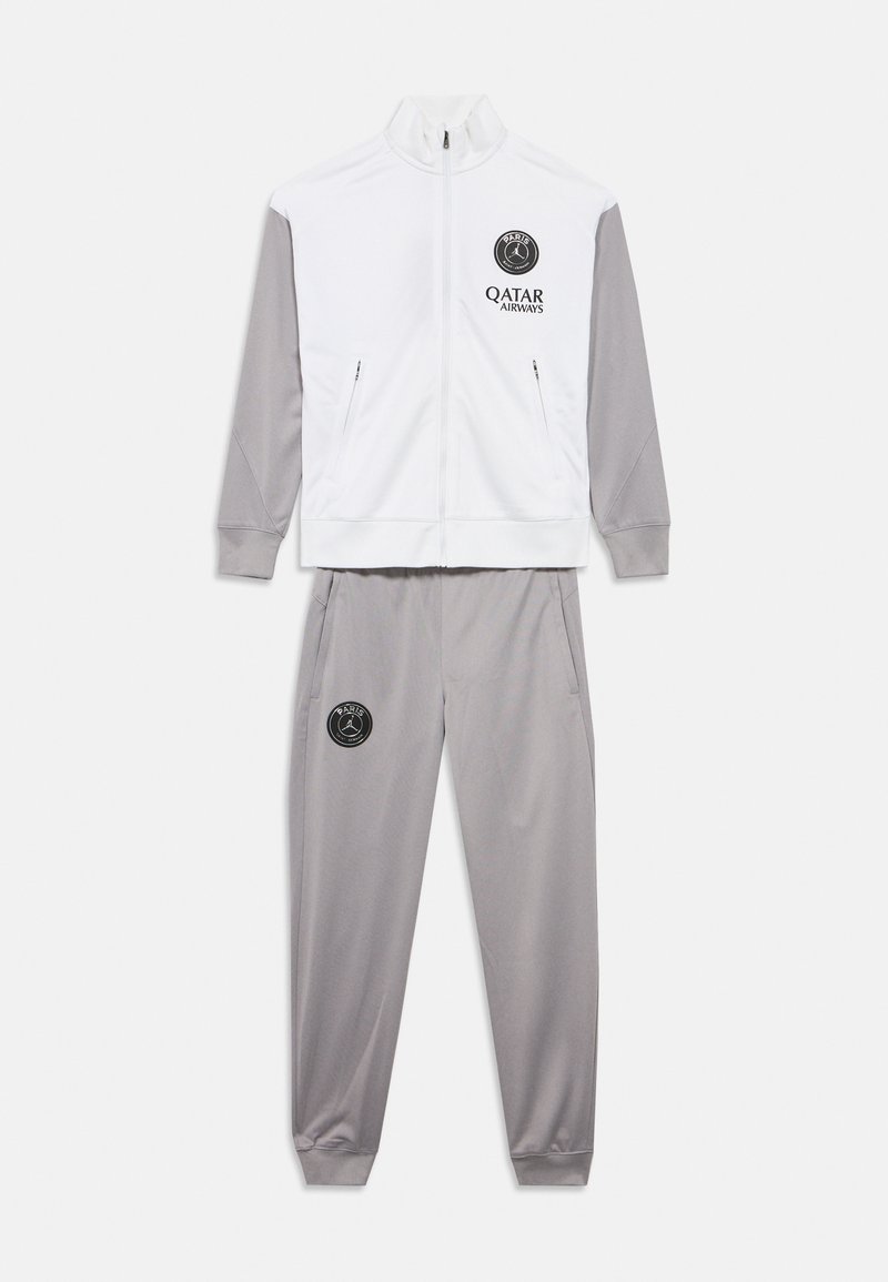 Λευκό τζάκετ φόρμας με γκρι μανίκια, διαθέτει φερμουάρ στις τσέπες και λογότυπο. Γκρι παντελόνι με τσέπες και λογότυπο στον μηρό. Λείο ύφασμα.
