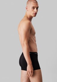 Zwarte boxershorts met een zachte elastische tailleband waarop het "Calvin Klein" logo staat. De stof lijkt glad en heeft een strakke pasvorm.