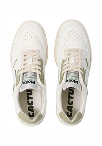 Białe sneakersy z zielonymi akcentami, skórka teksturowana, perforowana część palcowa i beżowe sznurowadła. Logo oraz informacje o rozmiarze widoczne na języku buta.