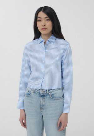 Camicia a righe blu chiaro e bianca con colletto, maniche lunghe e design cropped, abbinata a jeans in denim a vita alta.
