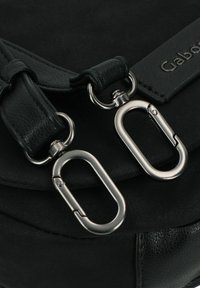 Zwarte leren tas met metallic zilveren sluitingen, getextureerde banden en een gladde oppervlakte. Inclusief een gemarkeerde leren label.