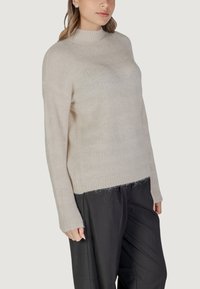 Helle beige Pullover mit Stehkragen, gerippten Bündchen und lockerer Passform. Hergestellt aus strukturiertem Strickmaterial, das dezente horizontale Streifen aufweist.