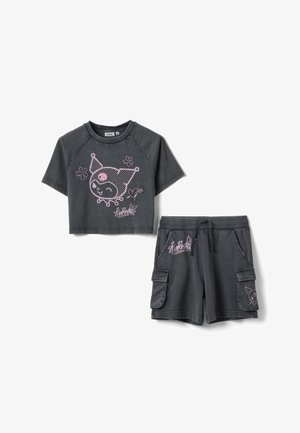 Chemisette courte gris foncé à manches courtes et short cargo assorti avec un personnage de dessin animé rose et des motifs floraux, et taille à cordon de serrage sur le short.