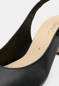 Μαύρο δερμάτινο παπούτσι slingback με χαμηλό τακούνι, μπεζ εσωτερική σόλα, χρυσό λογότυπο "GABOR" και μέγεθος 4½ σημειωμένο στο εσωτερικό.