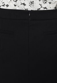 Černé kalhoty s oblekovým střihem a hladkou texturou, vybavené zadním zipem a dvěma skrytými kapsami, navržené ve slícovém siluetě.