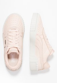Baskets Puma en cuir rose p âle, avec une tige perforée, une semelle blanche épaisse et des lacets assortis. Des accents texturés enrichissent le design.