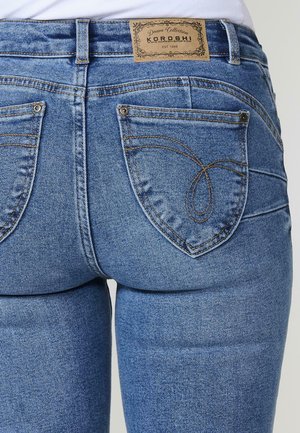 Jeans de mezclilla azul con un diseño ajustado, costuras visibles y dos bolsillos traseros. La cintura lleva una etiqueta de cuero con la marca.