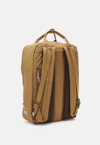 Ορθογώνιο καφέ σακίδιο με επενδεδυμένα λουριά ώμου, δύο χερούλια επάνω, τσέπη με φερμουάρ στο πλάι και πλέγμα στην πλάτη σε λευκό φόντο.