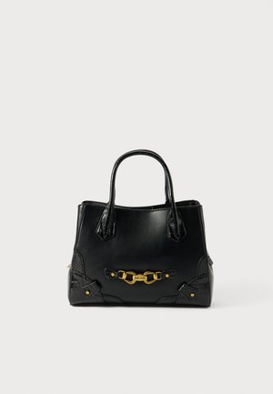 Černá kožená kabelka s dvěma uchy, zlatým kováním a texturovanými akcenty na dně, s pevným tvarem a zipovým uzávěrem.